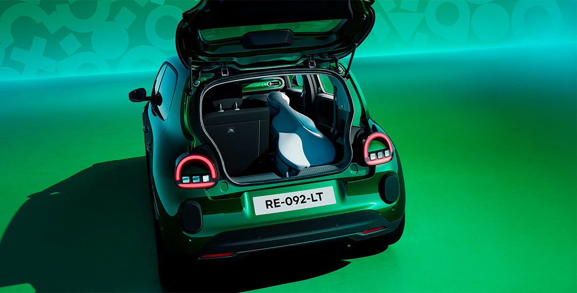 Absolu vihreä Renault Twingo E-Tech electric tavaratilan luukku avoimena, tavaratilassa soitinkotelo.