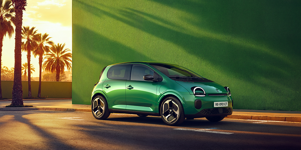 Absolu vihreä RenaultTwingo E-Tech electric aurinkoisella palmukadulla vihreää seinää vasten.