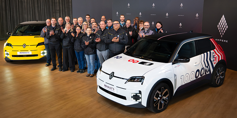 Keltaisen ja valkoisen Renault 5 E-Tech electricin välissä joukko iloisia ihmisiä.